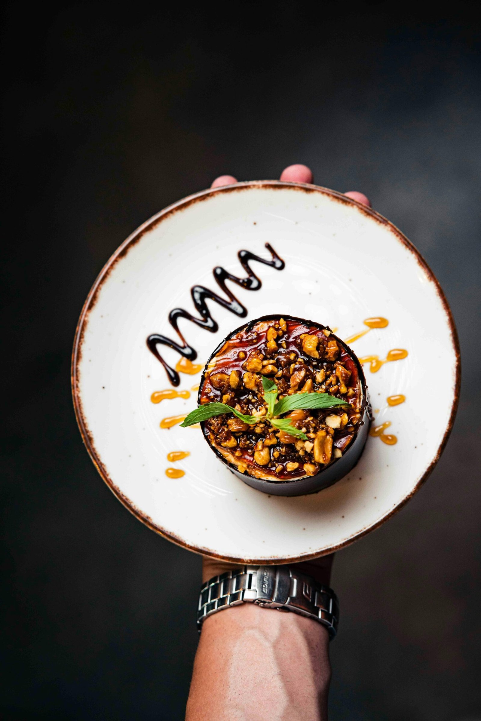 Artistic presentation of a gourmet dessert with caramel and chocolate drizzle on a rustic plate.